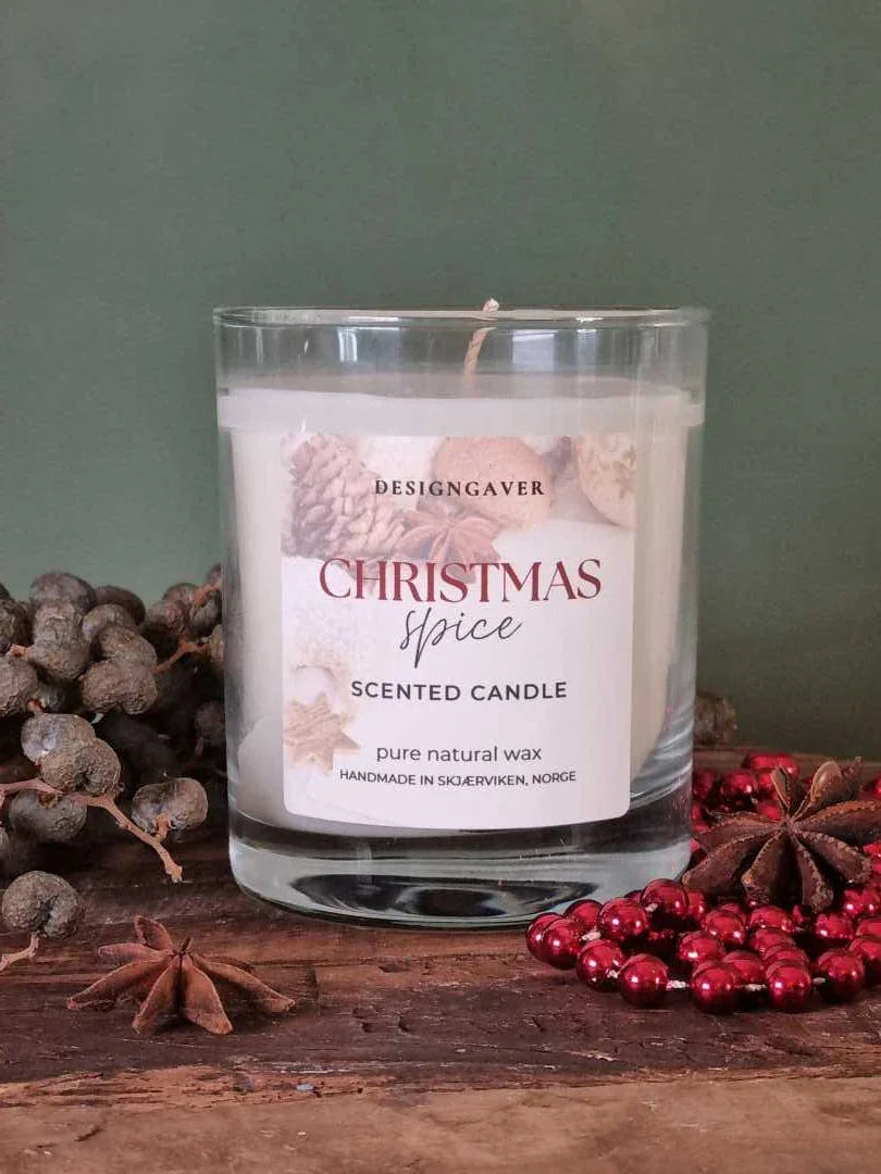 Et duftlys som står på et trefat med grønn bakgrunn. Dekoret med julepynt, og stjerneanis. Duftlyset heter Christmas spice og er fra designgaver. Lyset er laget i ren soyavoks og produsert i Skjærviken, Norge